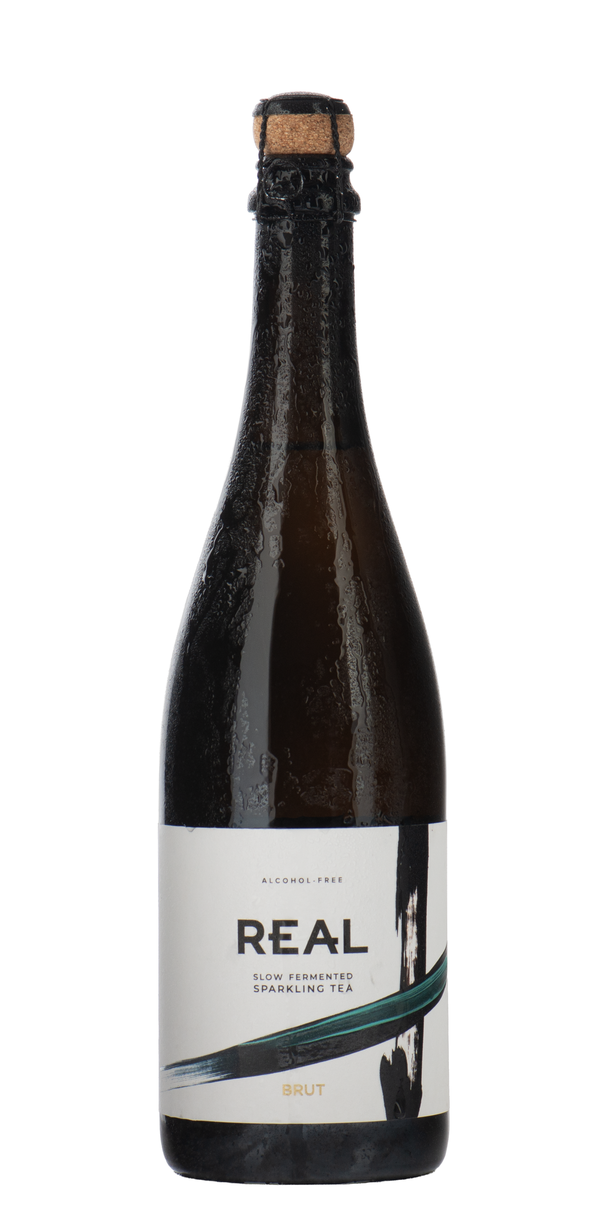 A dark glass bottle of REAL brand non-alcoholic slow fermented sparkling tea, Brut, with a cork stopper and a white label featuring black and green graphic elements, set against a plain white background.