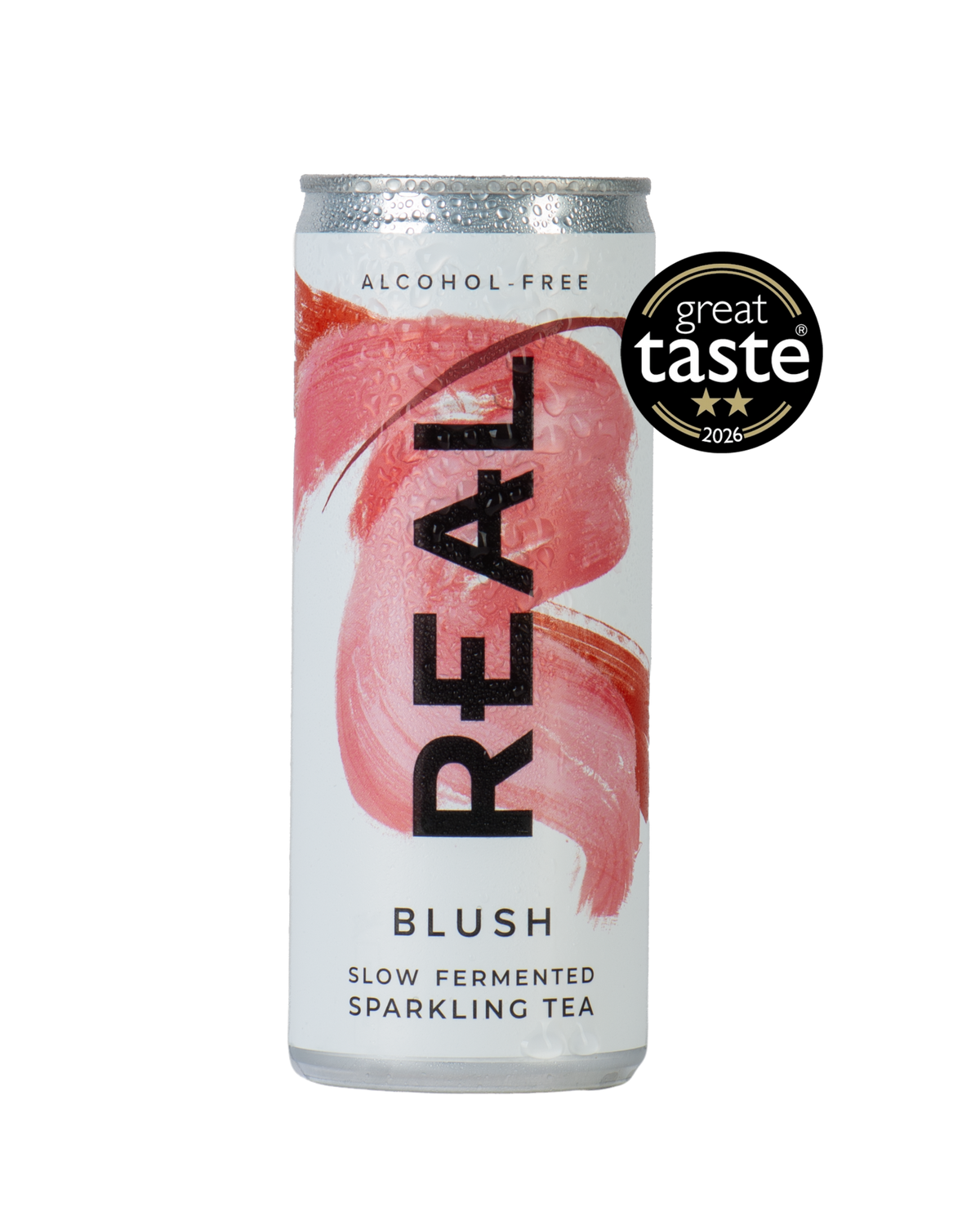 A silver aluminum can of REAL Alcohol-Free Blush Slow Fermented Sparkling Tea, featuring a pink brushstroke design and a black 'REAL' logo. A black 'great taste 2026' award badge is displayed on the top right of the can against a solid white background.