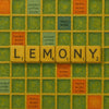 REAL Alcohol-Free artwork in oil painting style showing a Scrabble board with the word LEMONY spelled across the tiles