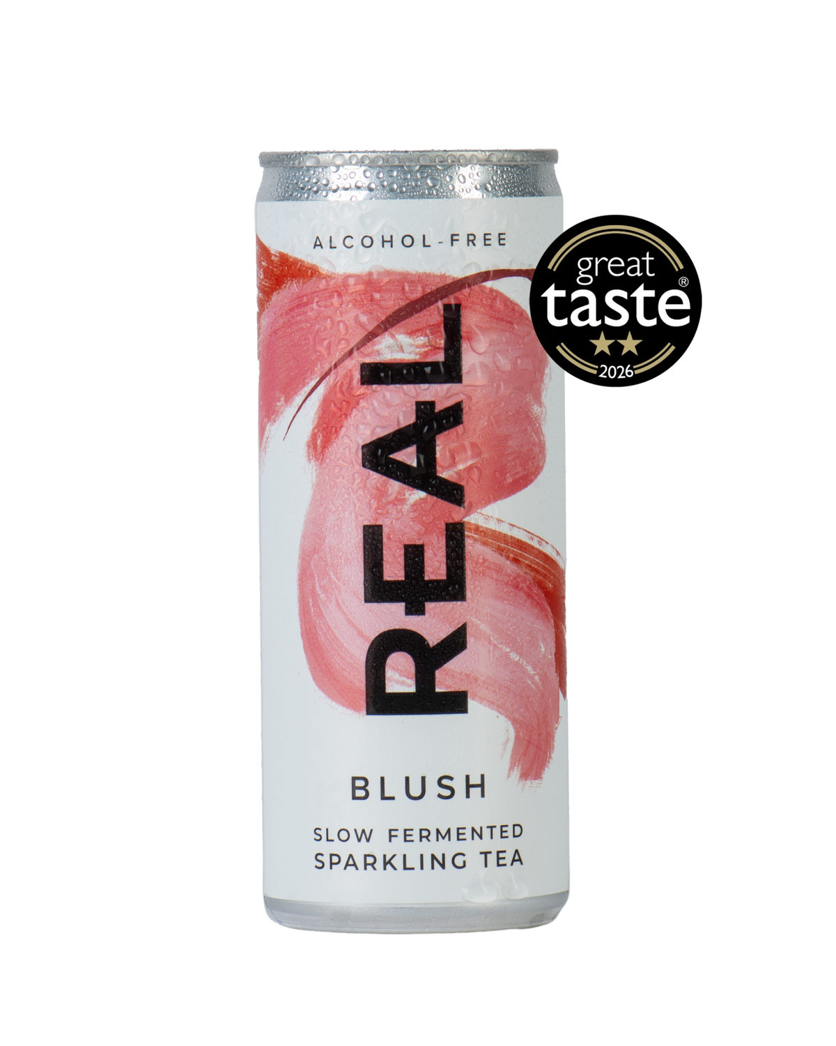 A silver aluminum can of REAL Alcohol-Free Blush Slow Fermented Sparkling Tea, featuring a pink brushstroke design and a black 'REAL' logo. A black 'great taste 2026' award badge is displayed on the top right of the can against a solid white background.