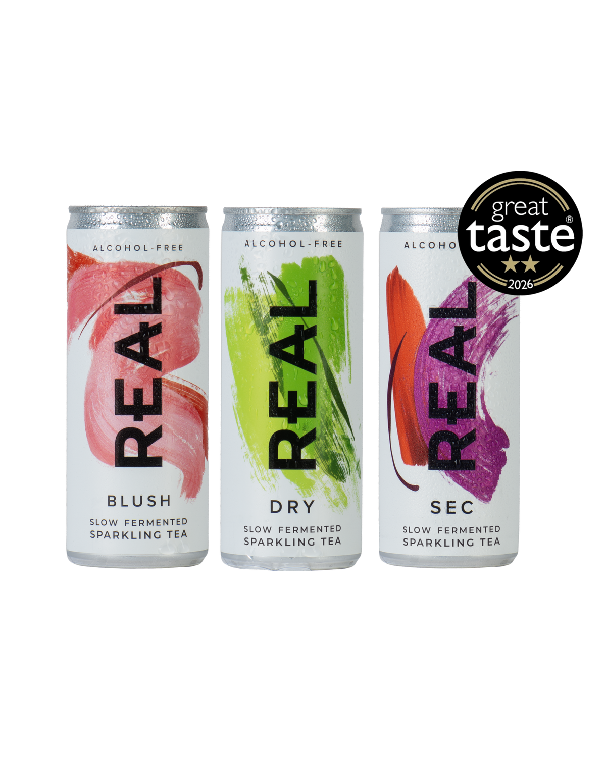 Three aluminum cans of REAL Sparkling Tea on a white background, with a black 'great taste 2026' badge in the top right. The cans are labeled BLUSH, DRY, and SEC, with pink, green, and orange-red abstract designs on white backgrounds.
